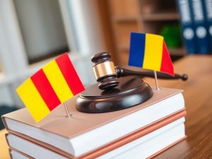 Balanță, coduri juridice, și drapel românesc pe masă.